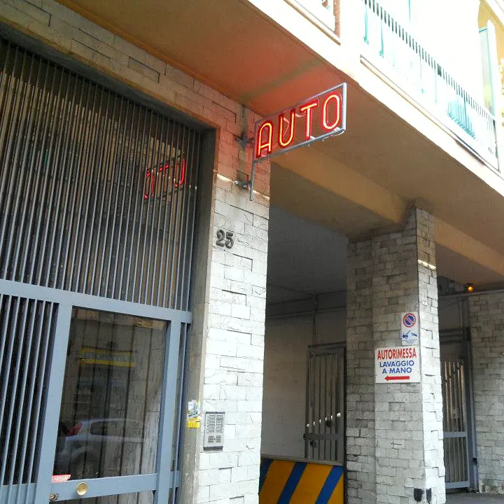 L'ingresso al civico 25 di Via Petrarca, con l'insegna al neon «AUTO» e il cartello «Autorimessa lavaggio a mano»